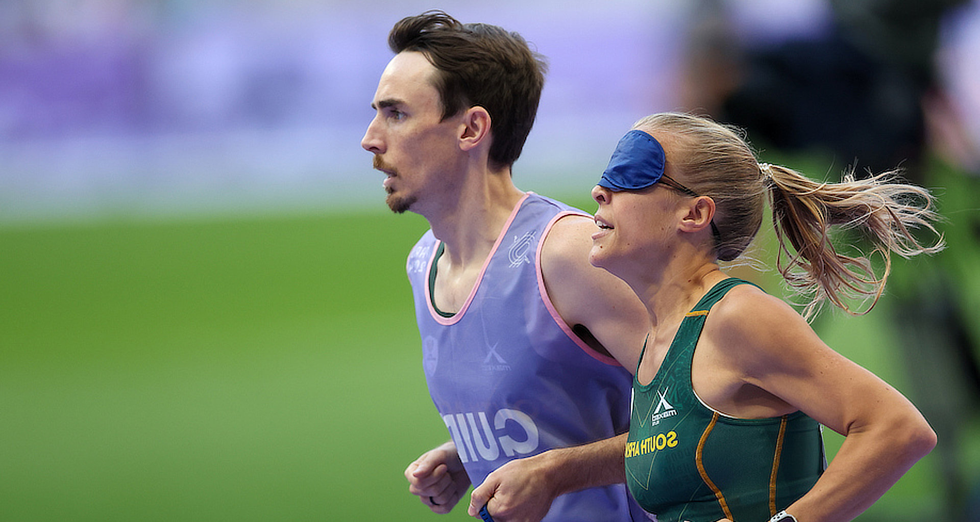 A photo of Louzanne and her guide running on the track at the Paralympics.